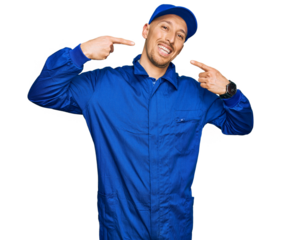 Bald man with beard wearing builder jumpsuit uniform smiling cheerful showing and pointing with fingers teeth and mouth. dental health concept.