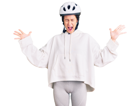 Beautiful brunette young woman wearing bike helmet and sporty clothes celebrating mad and crazy for success with arms raised and closed eyes screaming excited. winner concept