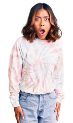 Young beautiful mixed race woman wearing casual tie dye sweatshirt afraid and shocked with surprise expression, fear and excited face.