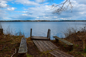 Fototapeta na wymiar Lake shore with a pier for boats and benches for relaxation