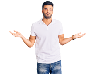 Young handsome hispanic man wearing casual clothes clueless and confused expression with arms and hands raised. doubt concept.
