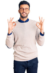 Fototapeta na wymiar Young handsome hispanic man wearing elegant clothes and glasses relax and smiling with eyes closed doing meditation gesture with fingers. yoga concept.