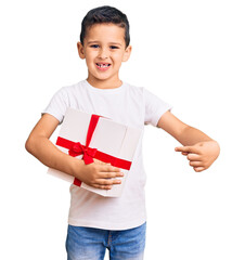 Little cute boy kid holding gift smiling happy pointing with hand and finger