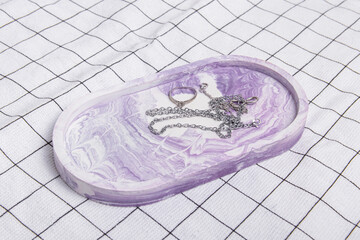 Jewelry on oval plaster tray. Checkered fabric