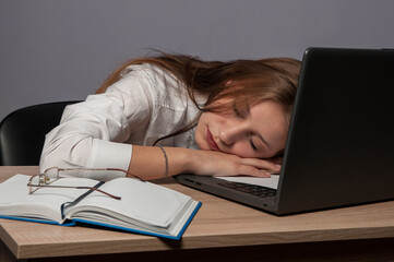 Tired girl at a table with a computer. work and fatigue. The student is sleeping at the table.