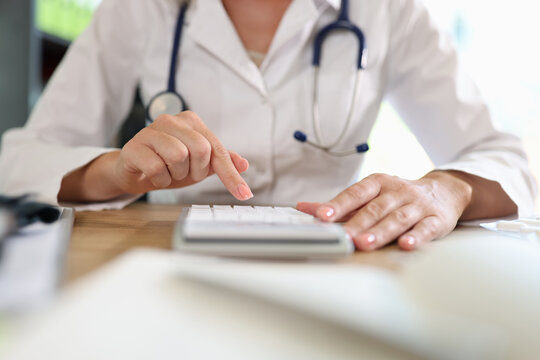 Woman doctor counting on calculator in office