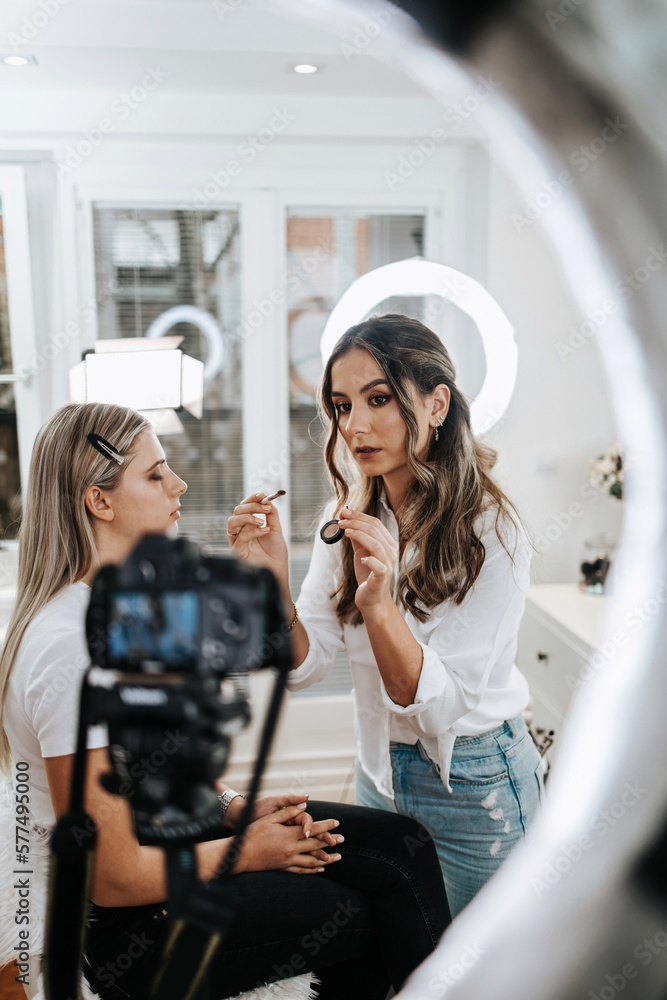 Wall mural happy young woman streaming a beauty makeup vlog from home or workshop. beautiful online content cre