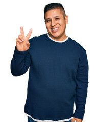 Young latin man wearing casual clothes showing and pointing up with fingers number two while smiling confident and happy.