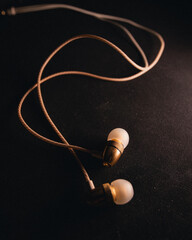 White and gold music earphones on a dark background