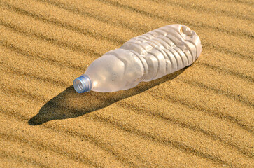 Plastic bottle on the beach sand. Plastic pollution of the ecosystem planet save concept