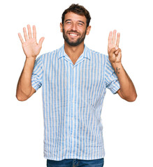 Handsome young man with beard wearing casual fresh shirt showing and pointing up with fingers number eight while smiling confident and happy.