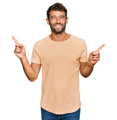 Handsome young man with beard wearing casual tshirt smiling confident pointing with fingers to different directions. copy space for advertisement