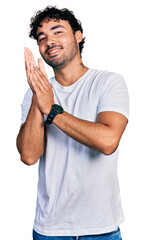 Hispanic young man with beard wearing casual white t shirt clapping and applauding happy and...