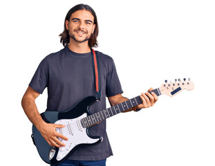 Young handsome man playing electric guitar looking positive and happy standing and smiling with a...