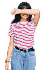 Young hispanic girl wearing casual clothes covering eyes with arm smiling cheerful and funny. blind concept.