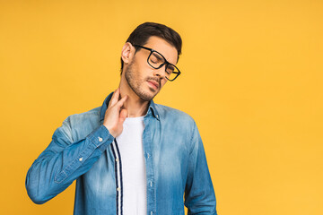 I need a massage. Frustrated man holding hand on his neck, having pain on the back. Man with beard in casual isolated on yellow background. Negative face expression.