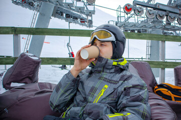 a snack at the ski resort. the guy drinks on the ski slope. mockup of a coffee cup