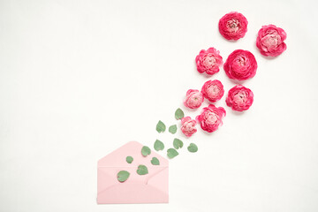 Love letter. white card with pink paper envelope mock up. Petals of flowers, roses and ranunculus. Valentine's day romantic background . Space for text.