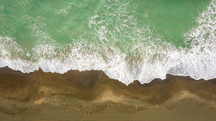 Perpendicular aerial view of the sea on a sand beach.