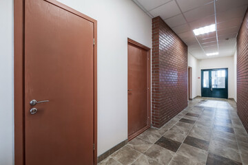 empty long corridor with red brick walls in interior of modern apartments, office or clinic.