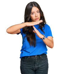 Beautiful brunette young woman wearing casual clothes doing time out gesture with hands, frustrated...