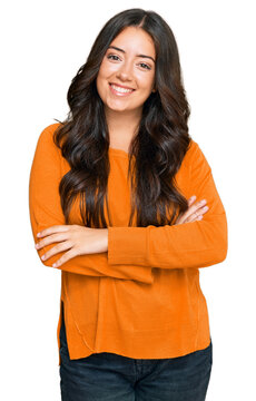 Beautiful brunette young woman wearing casual orange sweater happy face smiling with crossed arms looking at the camera. positive person.