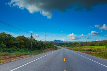 Fototapeta na wymiar beautiful road and mountain scenery in thailand,Asphalt road through the green field and clouds on blue sky in summer day. Beautiful grassland road in Thailand.Highland road.