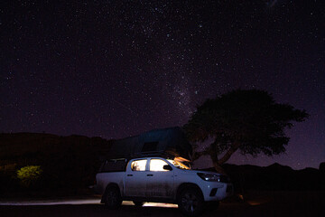 Milky way over a tent located on the roof of a pickup car in the Namib desert in Namibia. Night...