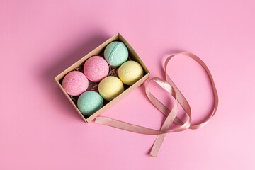 Bath bombs in gift box on pink background. Gift and ribbon. Packaging for gift, sale or delivery