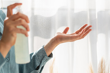 Caucasian women wipes her hands with an alcohol-based hand washing spray as a preventive hygiene.