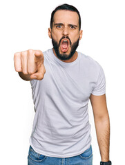 Young man with beard wearing casual white t shirt pointing displeased and frustrated to the camera, angry and furious with you