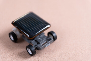 Small solar powered car with mini cells panel at the top. Solar powered toy car on kraft textured background, copy space