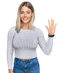 Beautiful blonde woman wearing casual clothes showing and pointing up with fingers number five while smiling confident and happy.
