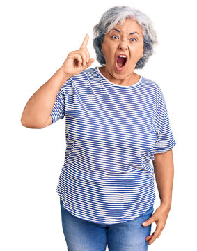Senior woman with gray hair wearing casual striped clothes pointing finger up with successful idea. exited and happy. number one.
