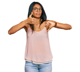 Young african american woman wearing casual clothes and glasses doing thumbs up and down, disagreement and agreement expression. crazy conflict