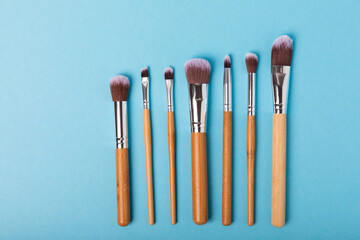 Set of cosmetic brushes on a blue background. Makeup brushes. Makeup tool. Beauty concept.Professional brushes for applying cosmetics eyeshadows, make-up powder. Place for text. Copy space. Flat lay.