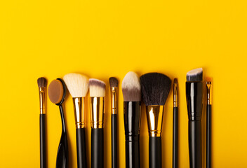 Set of cosmetic brushes on a yellow background. Makeup brushes. Makeup tool. Beauty...