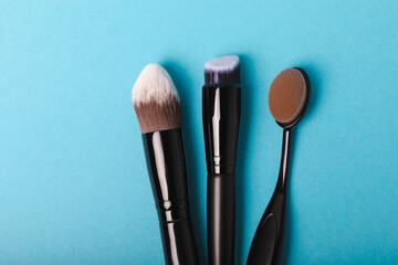 Obraz na płótnie Canvas Set of cosmetic brushes on a blue background. Makeup brushes. Makeup tool. Beauty concept.Professional brushes for applying cosmetics eyeshadows, make-up powder. Place for text. Copy space. Flat lay.