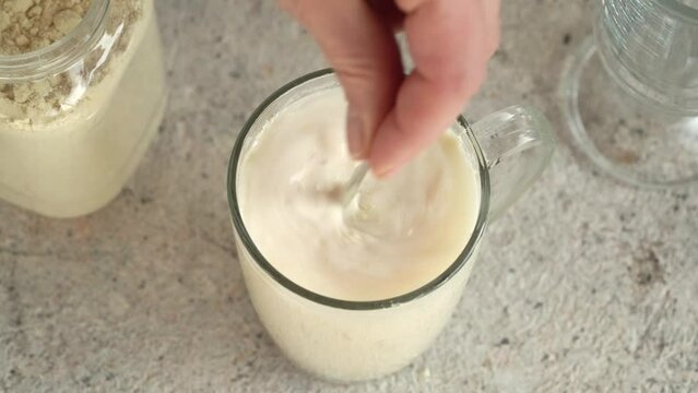 Mixing whey protein powder in a glass of water to prepare a fitness drink