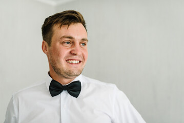 Man in a shirt and bow-tie on white background. Morning preparation groom at home. Fashion photo of a man.