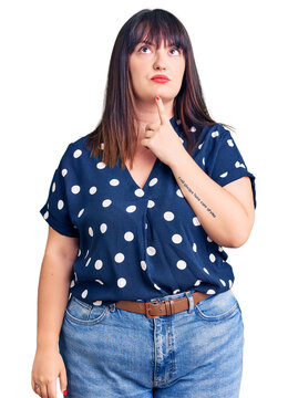Young plus size woman wearing casual clothes thinking concentrated about doubt with finger on chin and looking up wondering