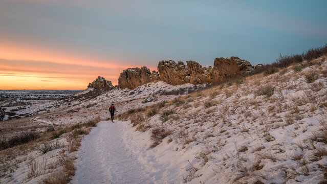 winter sunrise over a trail at Colorado foothills with a distant runner - Devils Backbone rock formation near Loveland