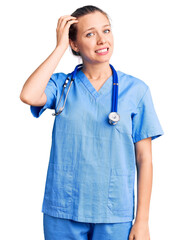 Young beautiful blonde woman wearing doctor uniform and stethoscope confuse and wonder about...