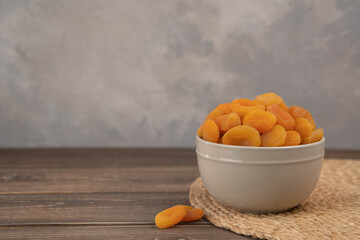 Bowl of dried apricots on the old wooden stand, selective focus.