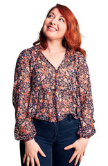 Young beautiful redhead woman wearing casual t-shirt looking away to side with smile on face, natural expression. laughing confident.