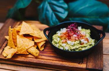 Guacamole mexicano con chips de nachos en tablero de madera
