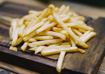 Patatas fritas doradas en una tabla de cortar de madera. Enfoque selectivo.
