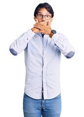 Handsome hispanic man wearing business shirt and glasses shocked covering mouth with hands for mistake. secret concept.
