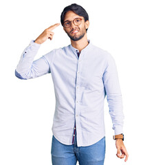 Handsome hispanic man wearing business shirt and glasses shooting and killing oneself pointing hand and fingers to head like gun, suicide gesture.