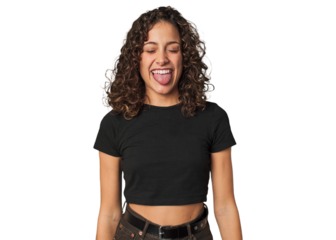Radiant young woman with stunning curls funny and friendly sticking out tongue.